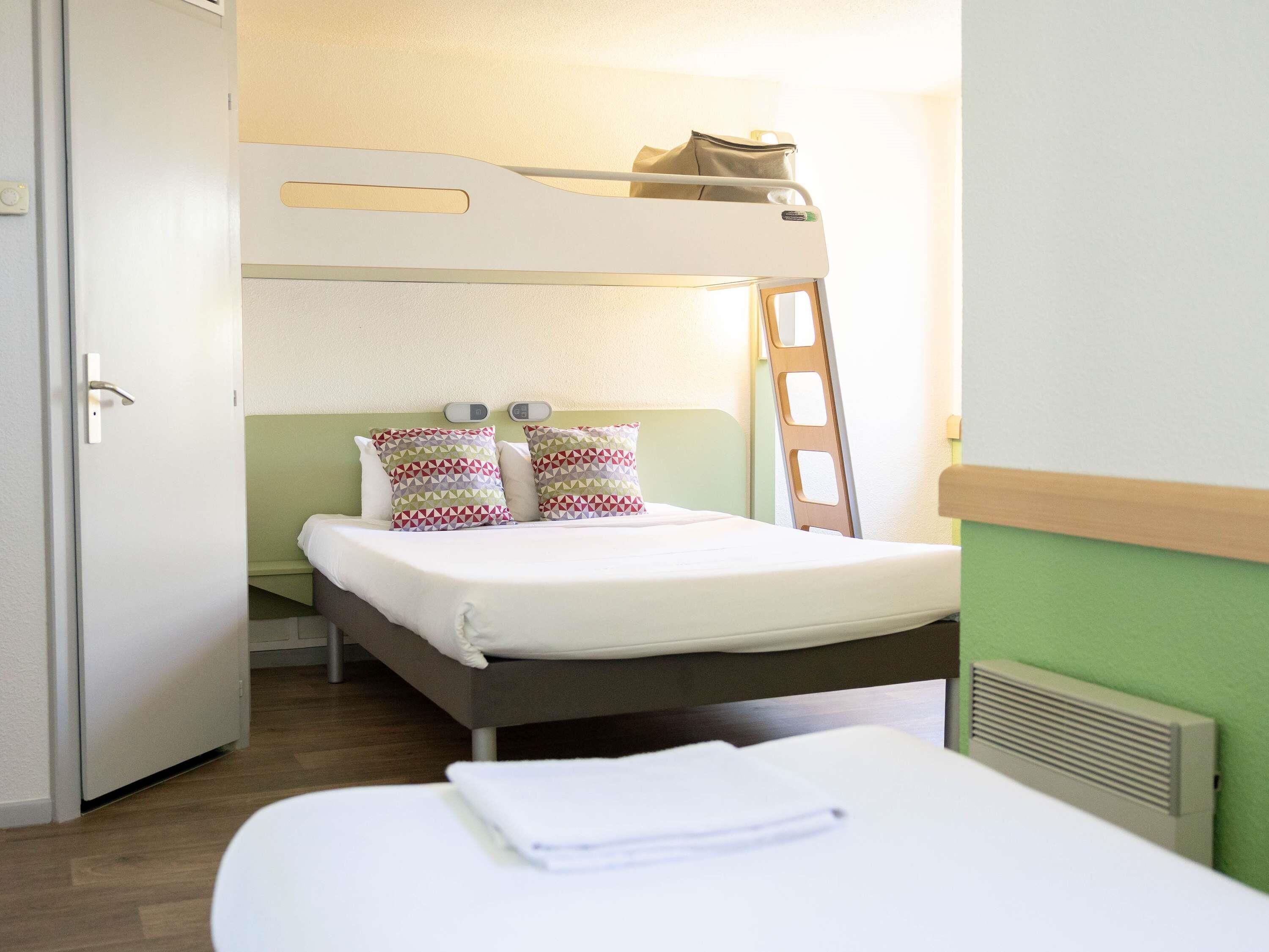 A bunk bed room with a ladder, a bedside table, and a door.