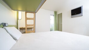A hotel room with a large bed, a TV mounted on the wall, and a window with curtains. - ibis budget Caen Nord Mémorial (Saint-Contest)