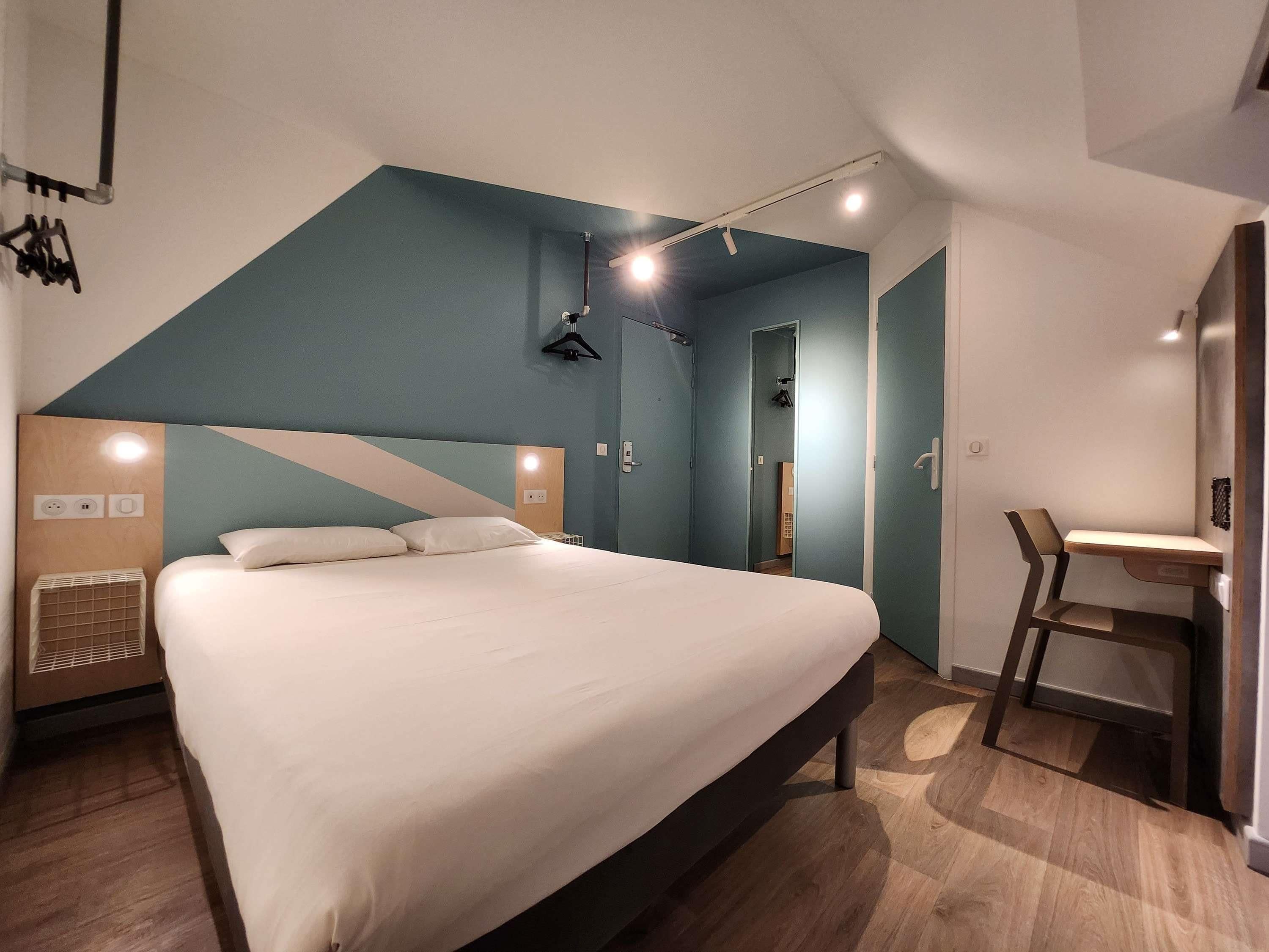 Una habitación de hotel moderna con una cama grande, un escritorio y una silla.