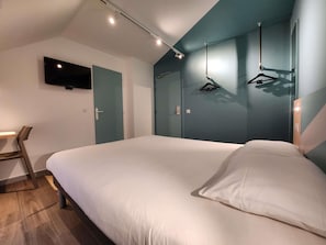 Ein Schlafzimmer mit Bett, Schreibtisch und Wandfernseher.