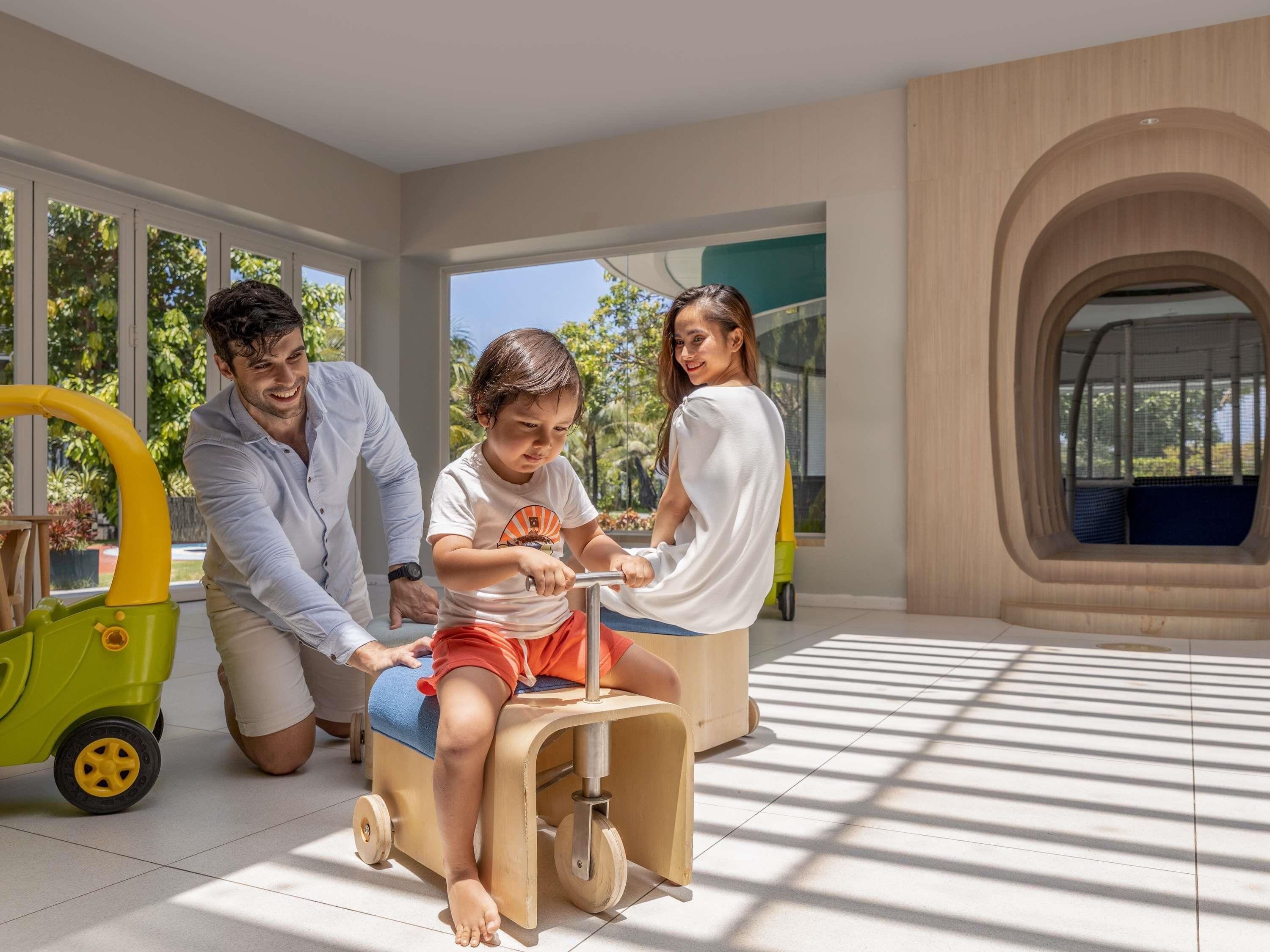 A spacious room with large windows, a child’s ride-on toy, and a modern architectural design.