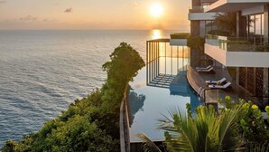Ein modernes Hotel mit Pool und Meerblick, einer Glasbrüstung und Sonnenuntergangssicht.
