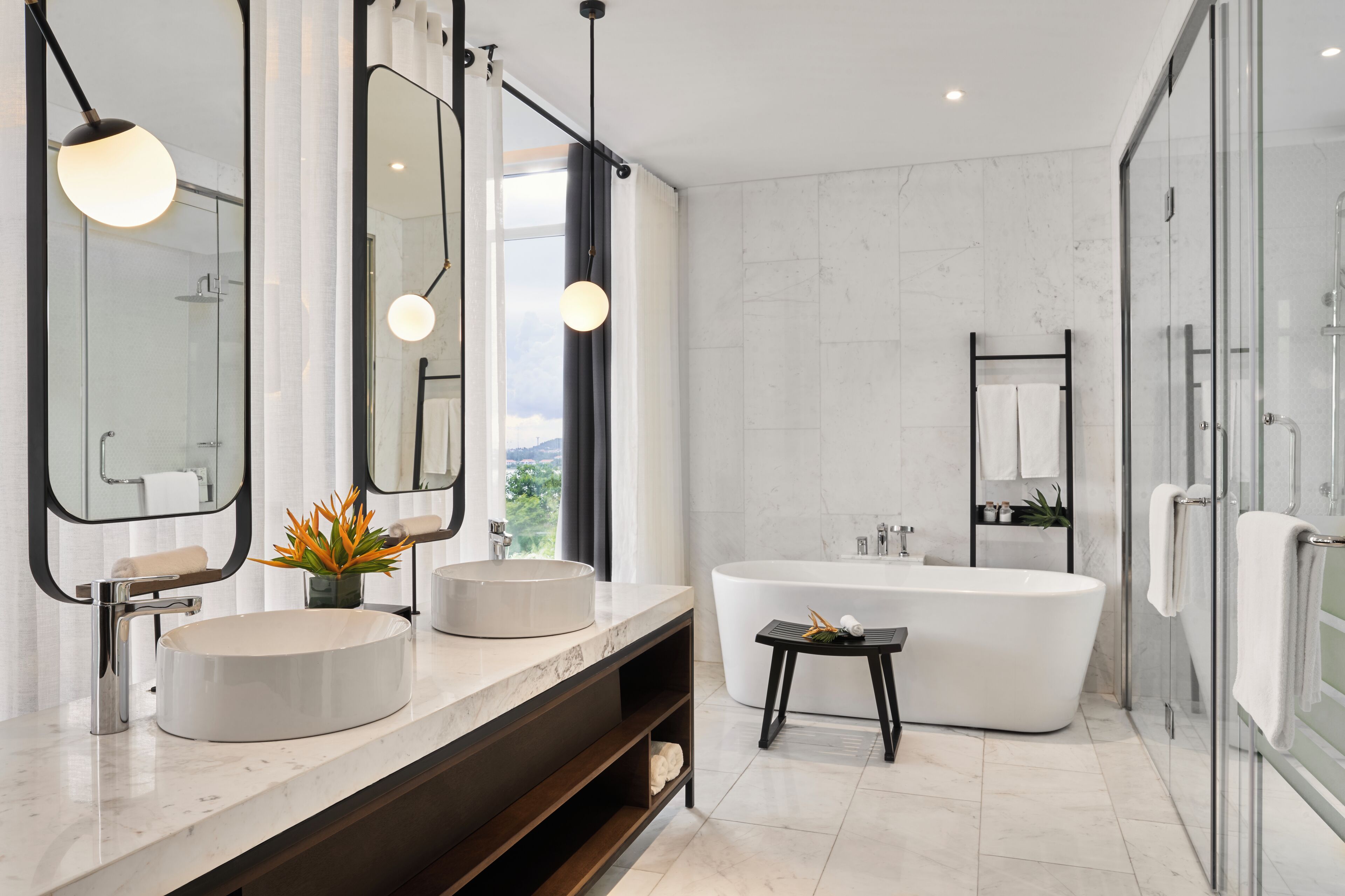 A modern bathroom with two sinks, a freestanding bathtub, and a glass-enclosed shower.