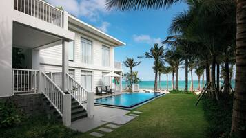A two-story house with a swimming pool, a balcony, and a view of the ocean.