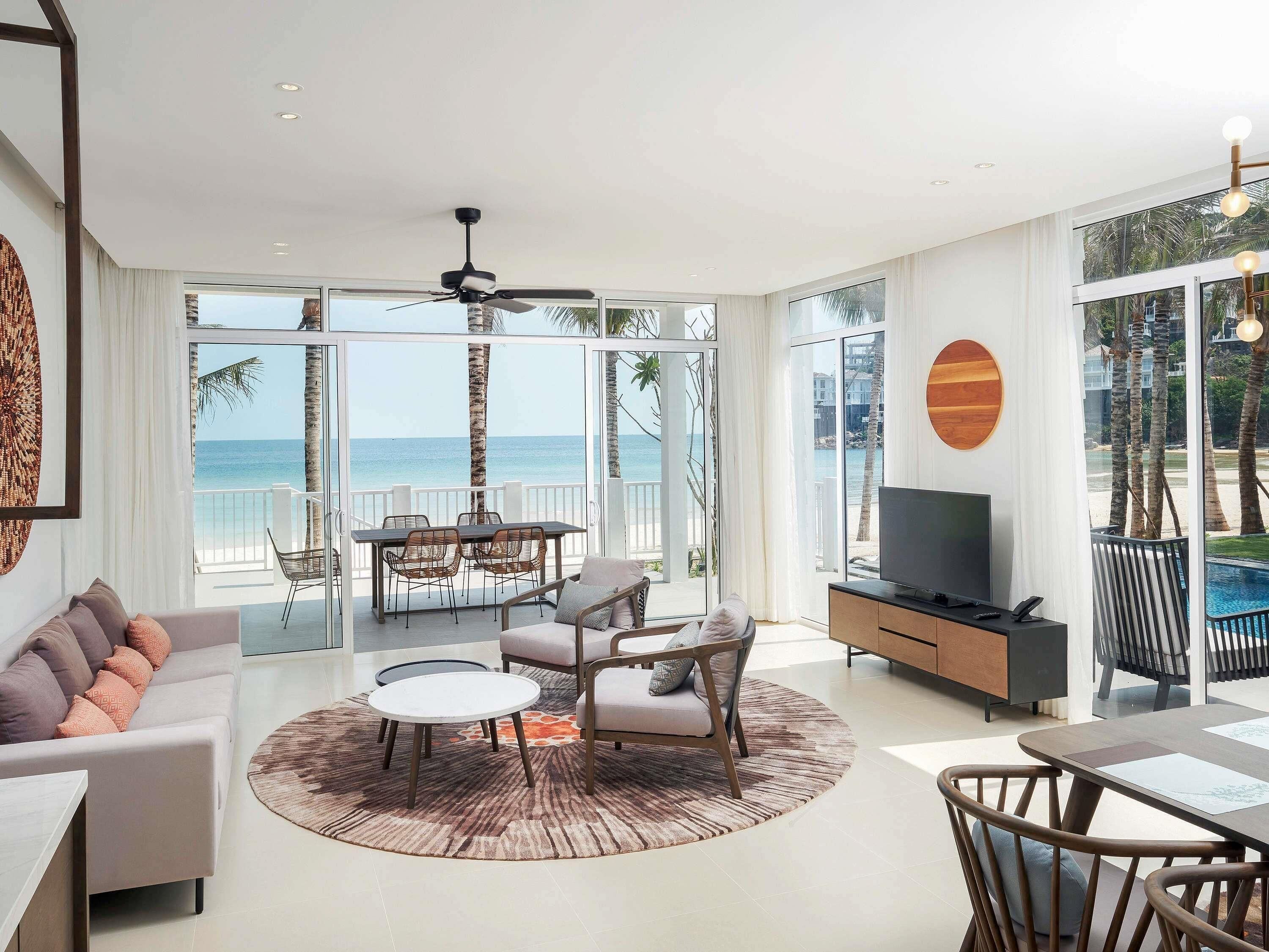A modern living room with a sofa, coffee table, TV, and a dining area with chairs and a table.