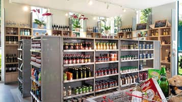 A grocery store with shelves stocked with various products, a shopping cart with items, and a teddy bear.