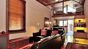 Una sala de estar amplia con techo alto, comedor y cocina.