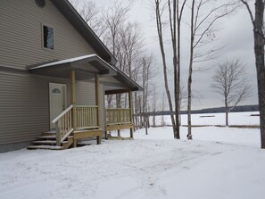 A two-story house with a wooden porch and steps leading to a door.