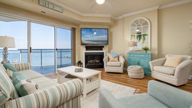 A living room with a television, a fireplace, and a view of the ocean.