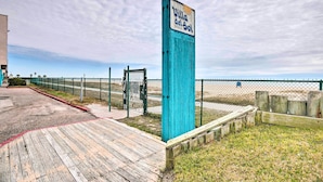 Une promenade en bois mène à une zone de plage où un panneau indique « Villa del Sol ».