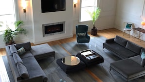 Ein großzügiges Wohnzimmer mit Kamin, Flachbildfernseher und mehreren Sitzgruppen.