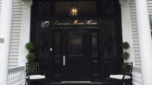 Eine schwarze Haustür, darüber steht "Emerson Mason House". Vor der Tür befinden sich zwei Stühle auf der Veranda.