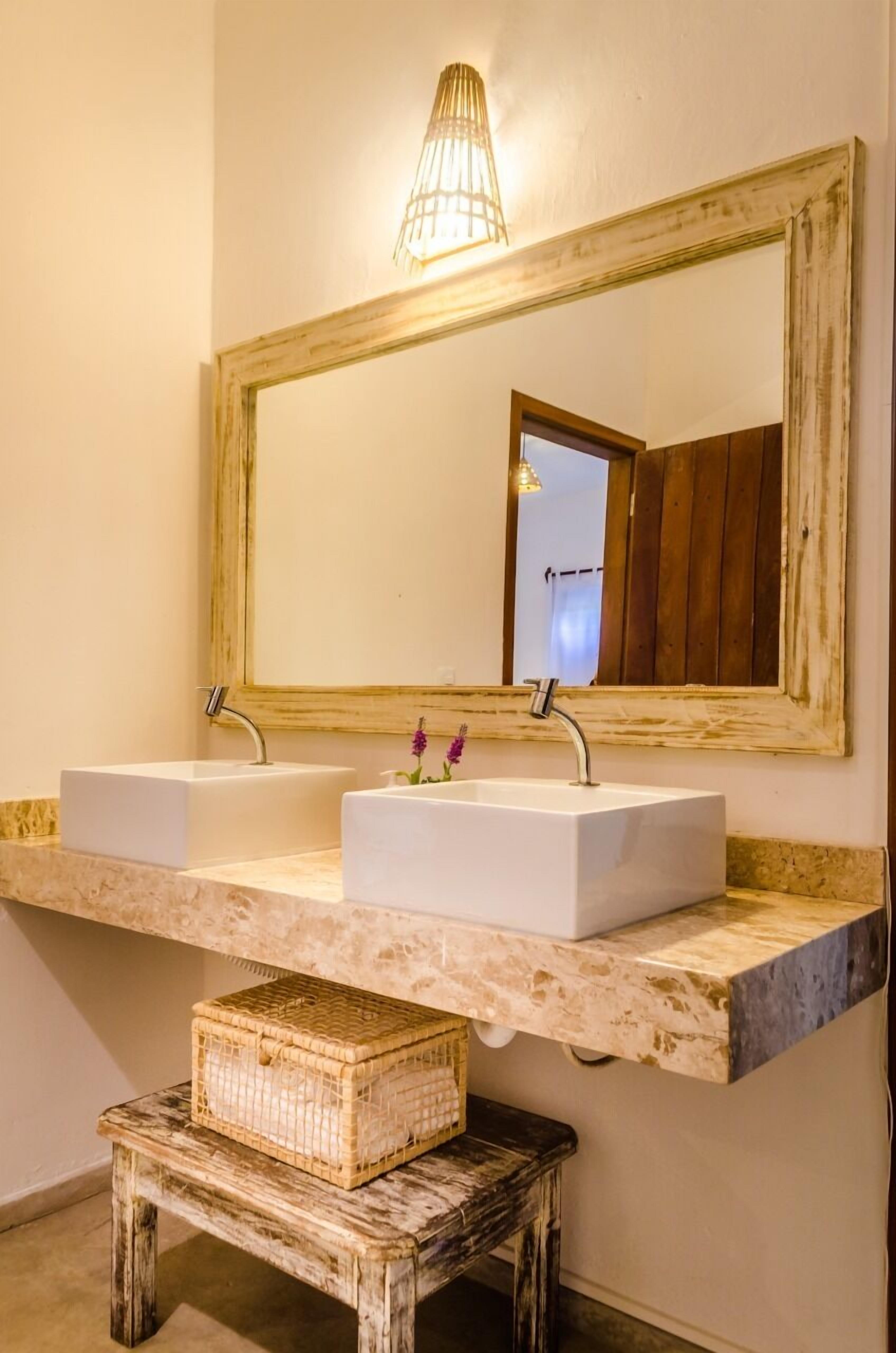 A bathroom with two sinks, a large mirror, and a small wooden stool.