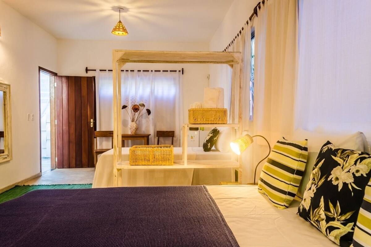 Une chambre à coucher avec un lit, une table de chevet, une lampe et une fenêtre avec des rideaux.