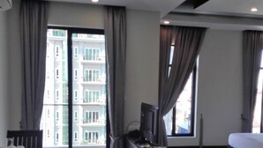 Una habitación de hotel moderna con un ventanal grande, una cama, un escritorio y un televisor.