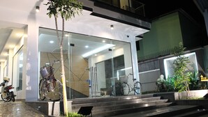 Un edificio moderno con puertas de vidrio, escalones que conducen a la entrada y bicicletas estacionadas afuera.