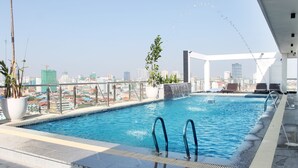 Una piscina en la azotea con agua azul cristalina, rodeada por una barandilla de metal y plantas en macetas.