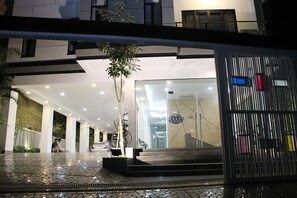 A modern hotel entrance with a glass facade, a staircase leading to the lobby, and a metal gate with colorful panels.