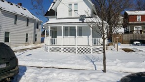 A two-story white house with a covered porch and a chimney.