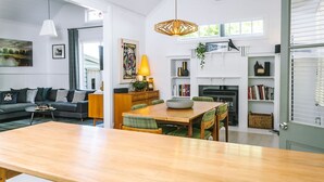 Un salon moderne avec un canapé, une table basse et un coin repas. On y trouve une cheminée, des étagères et une fenêtre donnant sur un beau paysage.