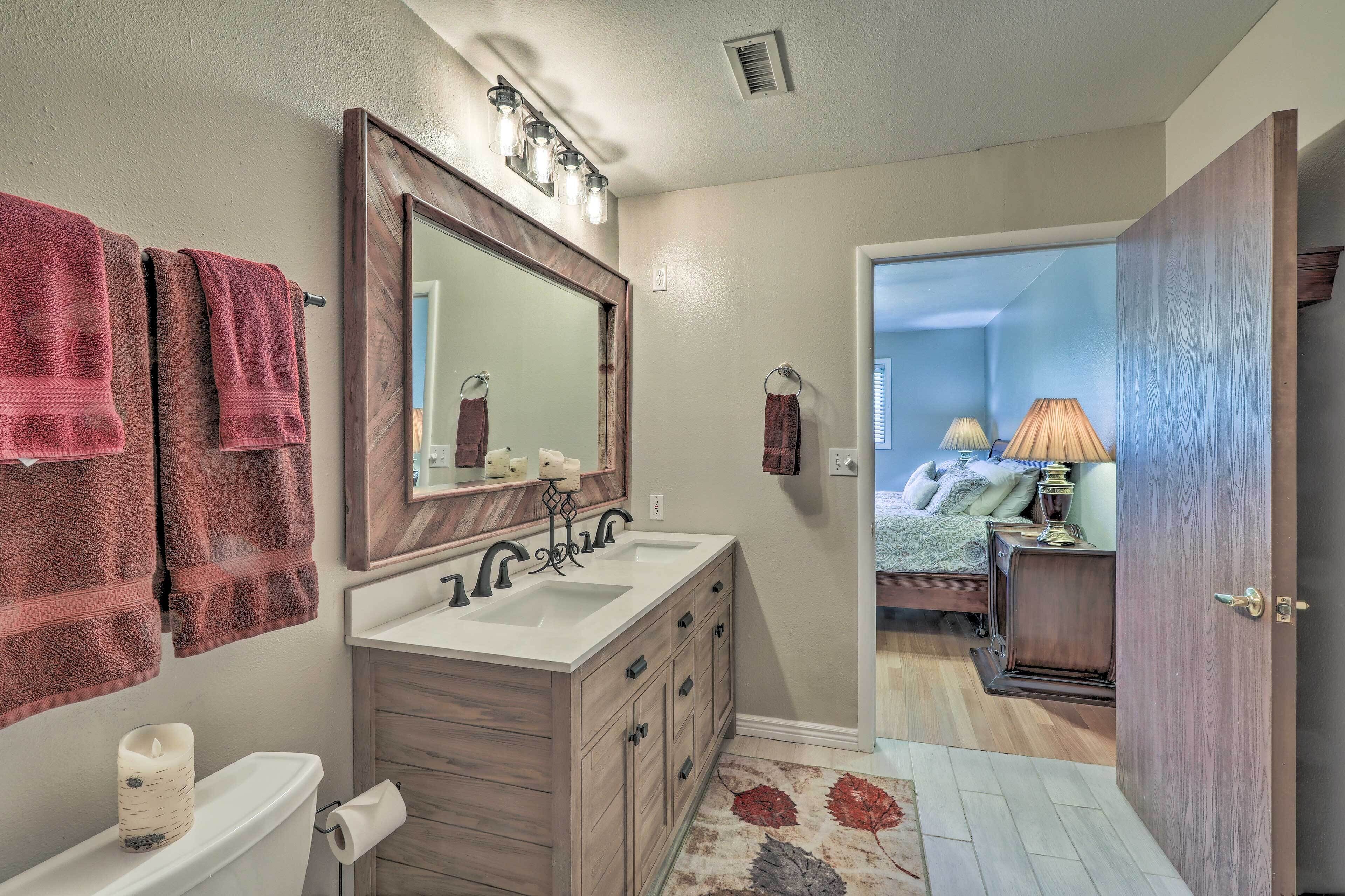 A bathroom with a double sink, a large mirror, and towels hanging on the wall.