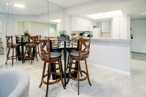 A modern kitchen with white cabinets, a central island, and bar stools.