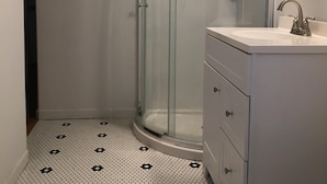Une salle de bain avec une douche à parois de verre, un lavabo blanc avec un miroir et des toilettes.