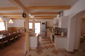 Eine geräumige Küche mit Holzbalken, einem Essbereich mit Stühlen und einem Kühlschrank.