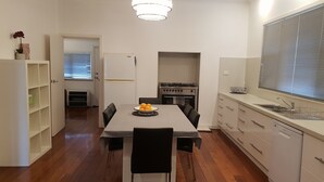 Une cuisine moderne avec un coin repas, un plancher en bois et un lustre.