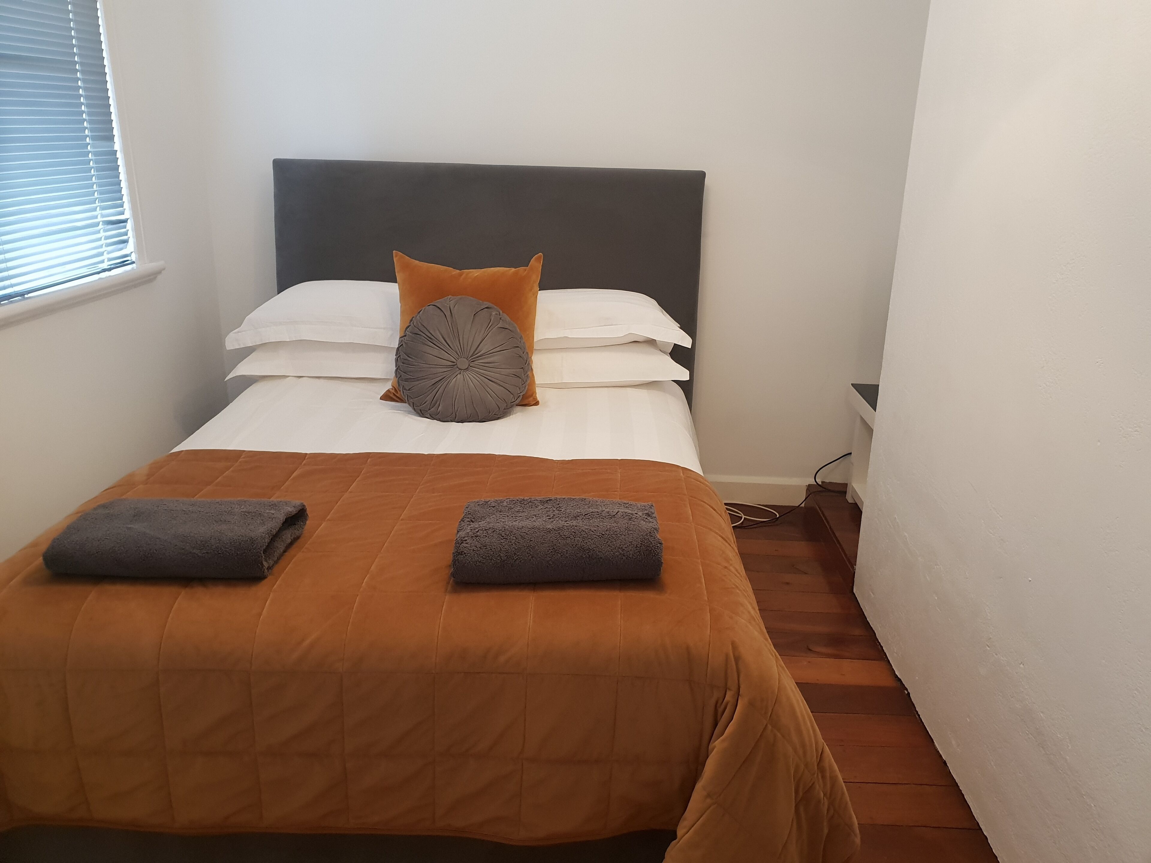A neatly made bed with a brown bedspread, two pillows, and two folded towels.