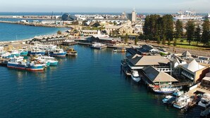 Un port de plaisance où sont amarrés plusieurs bateaux, un bâtiment imposant surmonté d’un dôme, et une vue dégagée sur l’eau et le paysage urbain lointain.