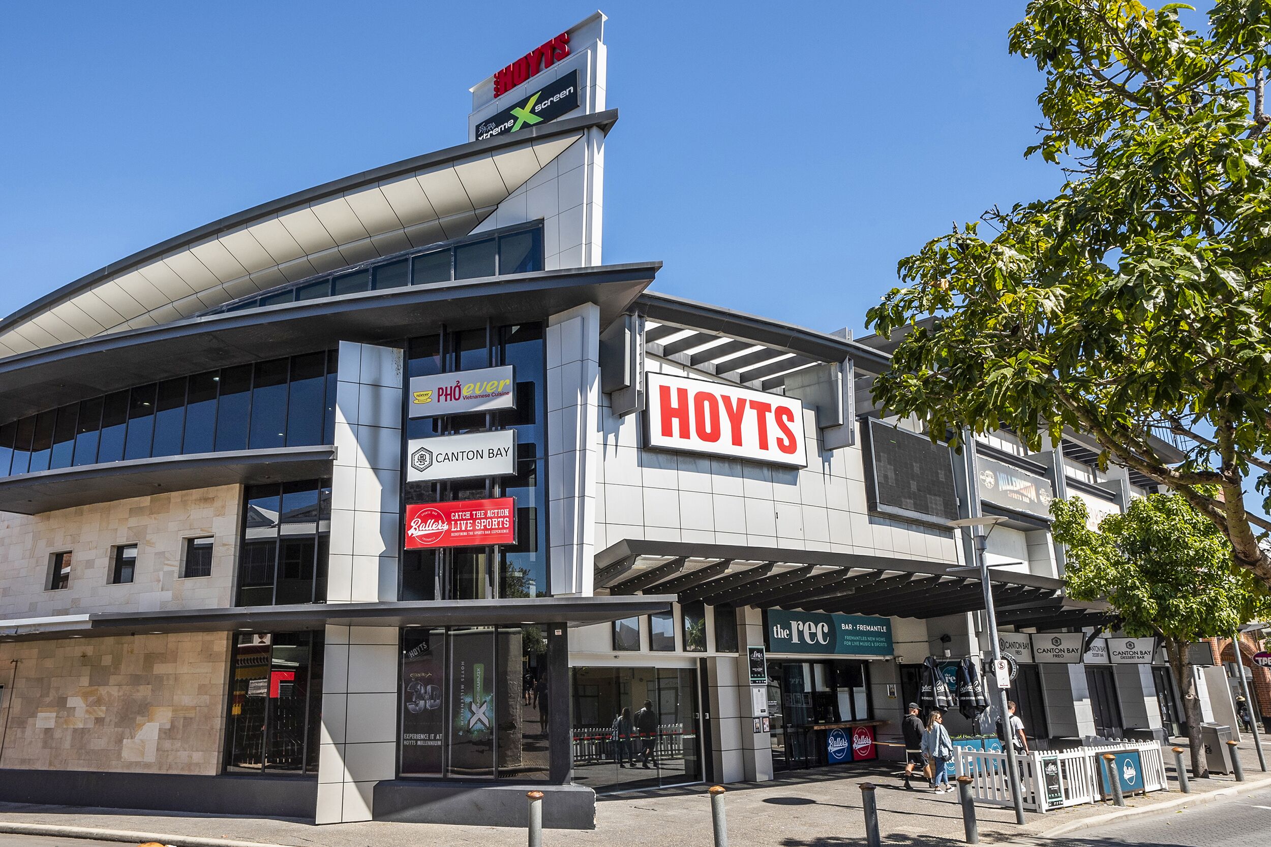 Ett modernt hotell med en tydlig skylt som visar ordet ”HOTELS”, en skylt med texten ”Canton Bay” och en skylt med texten ”Se sportevenemangen live”.
