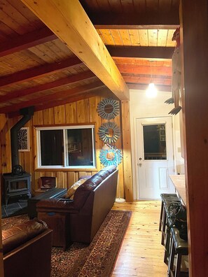 L’intérieur d’un chalet accueillant, avec un plafond en bois, un canapé, un tapis et une cheminée.