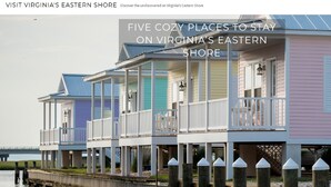 Une rangée de maisons colorées donnant sur le front de mer, dotées de balcons et d’une jetée qui s’avance dans l’eau.