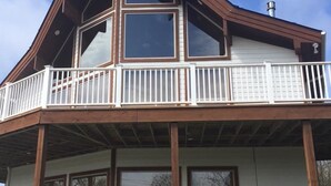 Une maison à deux étages dotée d’un balcon, de grandes fenêtres et de fondations en pierre.