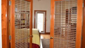 Une pièce avec des portes en bois, un ventilateur de plafond et une vue sur l’extérieur, visible à travers la porte.