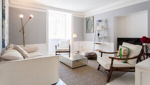Un salon moderne comprenant un canapé, des fauteuils, une table basse et un lampadaire.