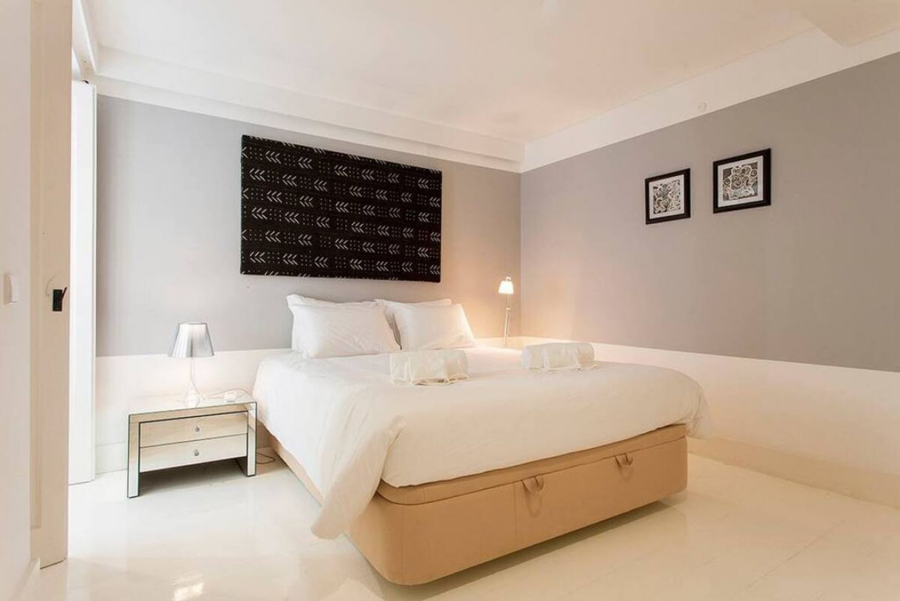 Une chambre moderne avec un grand lit, des tables de chevet, une œuvre d’art murale et des tableaux encadrés.