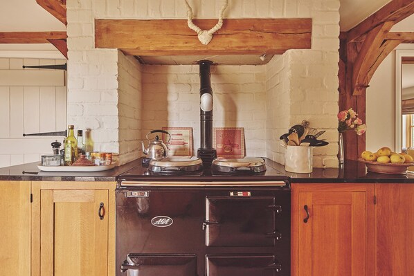 A kitchen with a vintage stove, wooden cabinets, and a brick wall.
