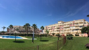 Ein Hotel mit mehreren Balkonen, einem Schwimmbad und Palmen.