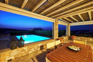 A covered outdoor area with a pool, stone walls, wooden furniture, and lanterns. - Villa with private wind-sheltered pool, fab seaviews, walking distance to Beach (Paros)