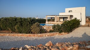 A modern house with a stone exterior, a swimming pool, and a gravel driveway. - Villa with private wind-sheltered pool, fab seaviews, walking distance to Beach (Paros)