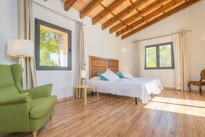 A bedroom with a bed, a green armchair, a wooden ceiling, and large windows. - VILLA PINS - Villa with private pool in Portocolom. Free WiFi (Portocolom)