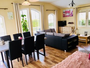 A cozy living room with a sofa, dining table, chairs, and a TV.