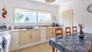 Una cocina con ventana, un reloj y una mesa de comedor con sillas.