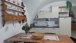 A kitchen with white cabinets, a wooden table with a vase of red flowers, and a black countertop. - LA FONTANA large and comfortable, with 3 bedrooms, terrace and Wi-Fi (Montagnaga)