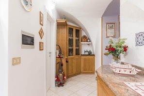 A kitchen with wooden cabinets, a sink, and a microwave. There is a decorative gnome statue and a vase with flowers on the counter.