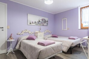 A bedroom with two beds, a dresser, a mirror, and a painting on the wall. - LA FONTANA large and comfortable, with 3 bedrooms, terrace and Wi-Fi (Montagnaga)