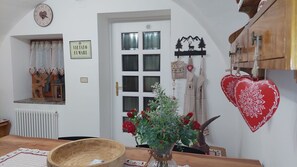 A cozy room with a wooden table, a vase with red flowers, a white door with frosted glass panels, and a wall clock. - LA FONTANA large and comfortable, with 3 bedrooms, terrace and Wi-Fi (Montagnaga)