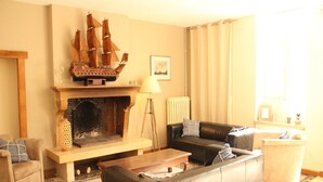 A living room with a fireplace, a large ship model, a sofa, and a coffee table. - Elegant Family Home in Bouix (Bouix)